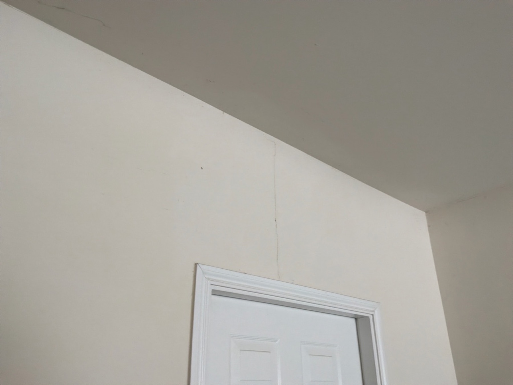 Foundation movement indoors — drywall crack climbing from a door frame toward the ceiling