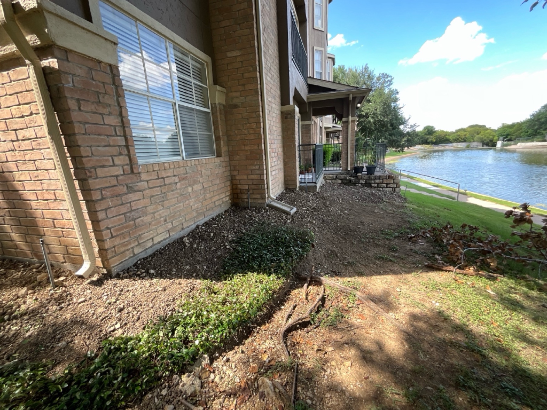 Re-graded beds along the building perimeter after repairs, restoring drainage slope
